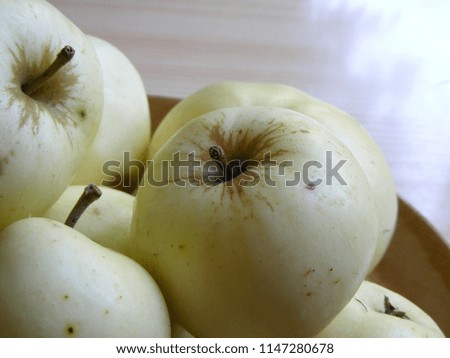 Fruit yield in summer time. Green apple fruits on the table in close up. Seasonal garden products in the kitchen. Delicious food for healthy life style and vegans. Raw material for cakes and sweets.