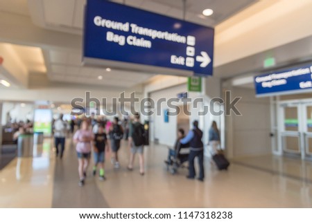 Blurred motion people walking with luggage and wheelchair service at American airport. Abstract blurry passengers or tourist with bag. Defocused traveler and handicap disabled at hallway terminal