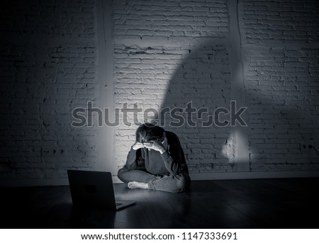 Sad and scared female Young woman with computer laptop suffering cyberbullying and harassment being online abused by stalker or gossip feeling desperate and humiliated in cyber bullying concept. Royalty-Free Stock Photo #1147333691