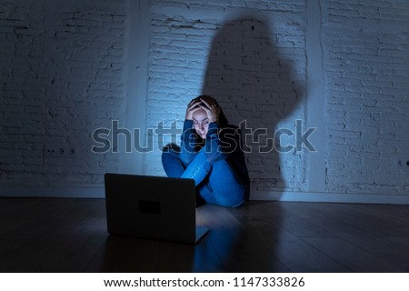 Sad and scared female Young woman with computer laptop suffering cyberbullying and harassment being online abused by stalker or gossip feeling desperate and humiliated in cyber bullying concept. Royalty-Free Stock Photo #1147333826