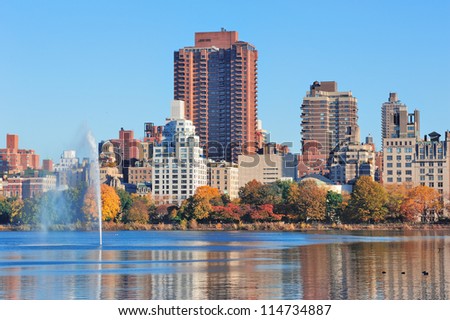 Fountain over lake in New York City Manhattan Central Park with skyscraper buildings and colorful Autumn foliage and clear blue sky.