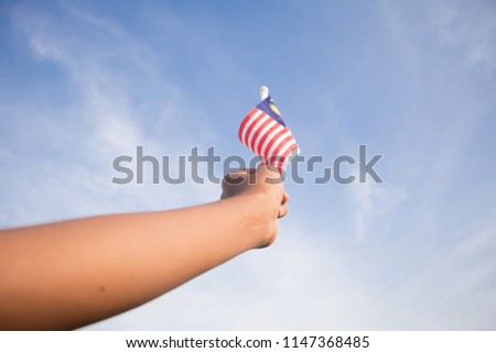 Independence Day concept. A happy and proud boy holding Malaysian flag. Sky background.