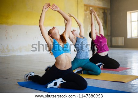Yoga class, pilates, fitness, flexibility, activity and healthy lifestyle. Fit sporty women stretching working out together in gym