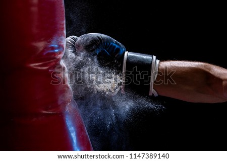 Close-up hand of boxer at the moment of impact on punching bag over black background Royalty-Free Stock Photo #1147389140