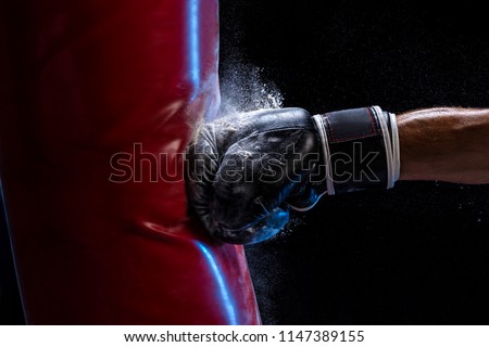 Close-up hand of boxer at the moment of impact on punching bag over black background Royalty-Free Stock Photo #1147389155