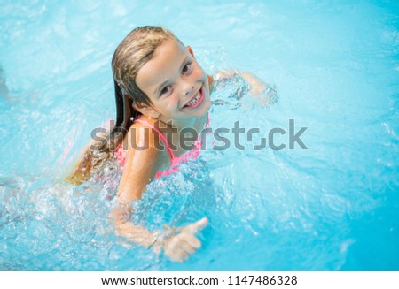 Smiling kid playing in pool. Looking at camera.