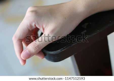  young woman putting her right hand on wooden armchair