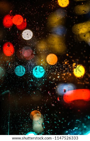 Artistic closeup through a car windshield over bokeh colorful street Christmas lights at night, like a pattern, with rain texture on the window, creating a fairy jazzy and romantic atmosphere, Paris.