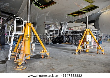 Aircraft (airplane) lift up from the floor by aircraft jack for maintenance at aircraft hangar.Aircraft on jack in hangar for maintenance service check by mechanic. Royalty-Free Stock Photo #1147553882