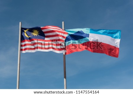 Malaysia and Sabah flag waving in the wind against a blue sky.