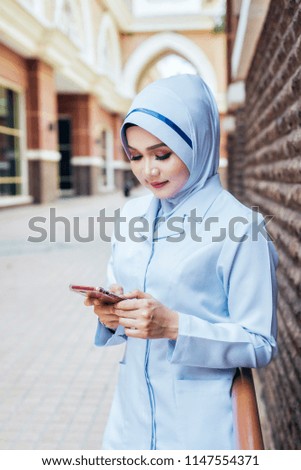 female hijab nurse posing and smiling holding mobile phone