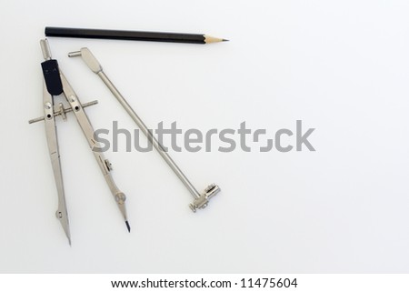 Drafting instruments on a piece of paper. A pair of compasses and a pencil are laid out in a symmetrical pattern.