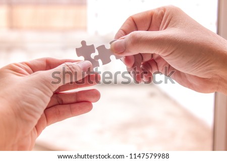Close up of two hands put 2 jigsaws/puzzle together meaning cooperation of people leading to success. business concept  Royalty-Free Stock Photo #1147579988