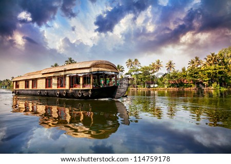 House boat in backwaters near palms at cloudy blue sky in Alappuzha, Kerala, India Royalty-Free Stock Photo #114759178