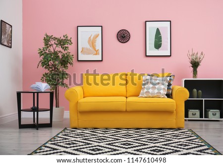 Modern living room interior with comfortable yellow sofa near color wall