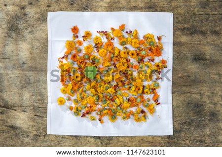 dried organic herbal healing calendula on napkin over wooden table