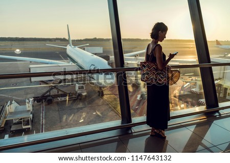 Beautiful young female on airport. Woman waiting for her airplane and using mobile phone. Flight application using to check in Royalty-Free Stock Photo #1147643132