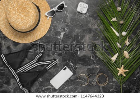 Flat lay composition with smartphone and beach objects on dark background