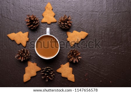 Coffee with cookies in shape of Christmas tree on a shabby dark brown background