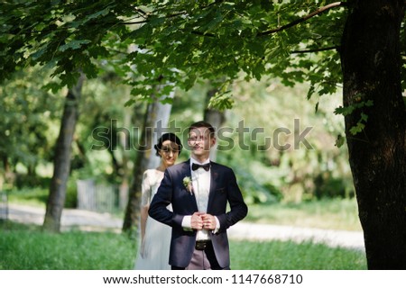 Fabulous wedding couple posing and hugging in the park on a beautiful summer day.
