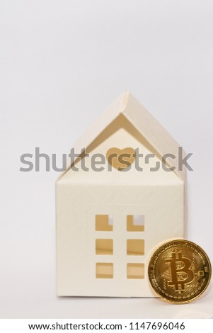 bitcoin coin and paper model house. conceptual image for paying a house using crypto currency.
