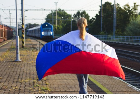 Travelling in Czech Republic by train. Woman with flag looking on arriving train on railroad station. Travel concept
