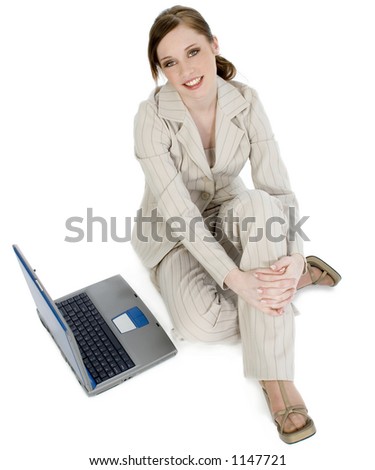 Beautiful young business woman in suit with laptop.  Sitting on floor. Smiling.