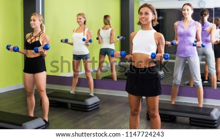 Portrait of athletic girls exercising with dumbbells in gym