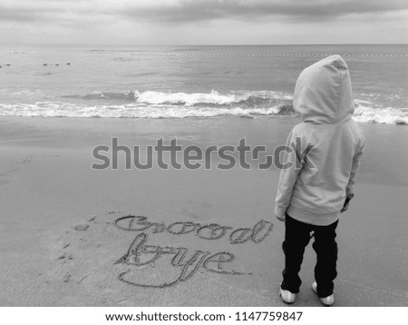 Black and white picture where a kid stand facing an open sea with a text goodbye