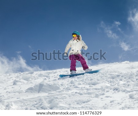 Young girl snowboarder in motion on snowboard in mountains