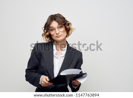 A woman in glasses holds a folder-tablet business in her hands.                               