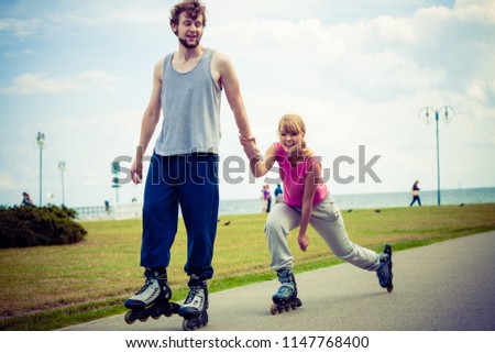 Active lifestyle people and freedom concept. Young fit couple on roller skates riding outdoors on sea coast, woman and man enjoying time together.
