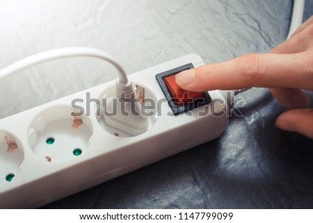 Female Hand Pressing Red Switch Of Multiple Socket Outlet, Saving Energy Concept Royalty-Free Stock Photo #1147799099