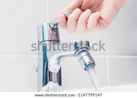 Female Hand On The Handle Of A Chrome Faucet With Running Water Royalty-Free Stock Photo #1147799147