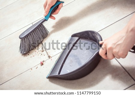 Female Hands Sweeping Dust With A Broom On A Dustpan, Housekeeping Concept Royalty-Free Stock Photo #1147799150