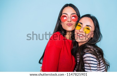 Friends forever. Two cute lovely girl friends in sunglasses posing with smile on blue background Royalty-Free Stock Photo #1147825901