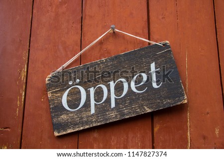 An old wooden vintage sign on a traditional red wood wall in Scandinavia with the word Open (Swedish: Oeppet) as a symbol that the store or restaurant is open for public in Sweden, Europe