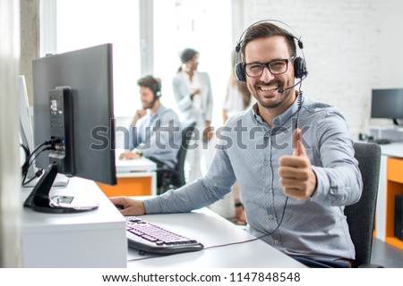 Happy male customer service operator showing thumb up in office. Royalty-Free Stock Photo #1147848548