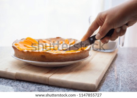Cutting delicious homemade lemon apricot pie with a sharp knife on wooden board