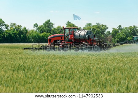 Self propelled sprayer applying pesticide to a wheat field. Pest control and protection for growing crops. Agricultural machinery. Royalty-Free Stock Photo #1147902533