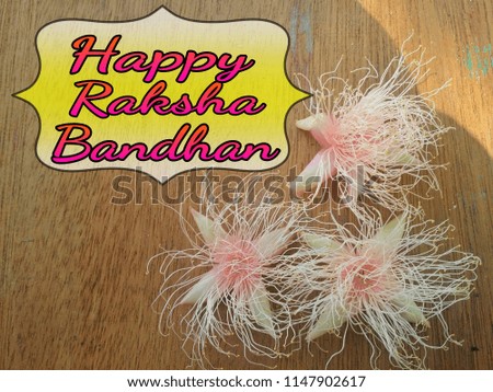 Concept of beautiful soft pink flower on wooden background with greeting word HAPPY RAKSHA BANDHAN