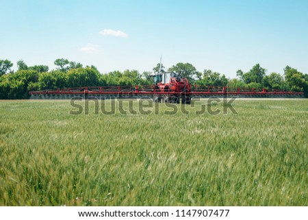Machine spraying water on plants in sunny weather. Irrigation, agriculture and farming. Royalty-Free Stock Photo #1147907477