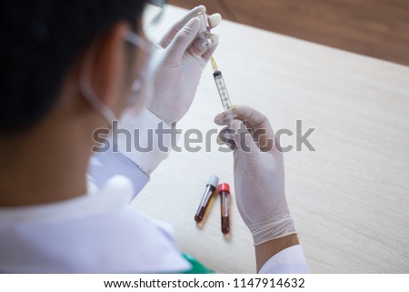 Close up Doctor is  injecting  patient vaccine in test tube with syringe and stethoscope in lab room . Laboratory environment  and medical concept .insulin or vaccination. Hospital office room.