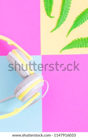 Headphones and green leave on color background in copy space. Cheerfulness concept.