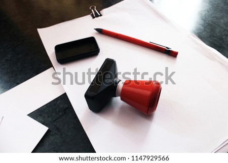 Office paper document stamp with Business cards, papers and red pen lying around.