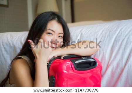 lifestyle natural portrait of young happy and beautiful Asian Korean tourist woman with travel suitcase arriving at hotel sitting on room floor excited and cheerful giving thumb up satisfied