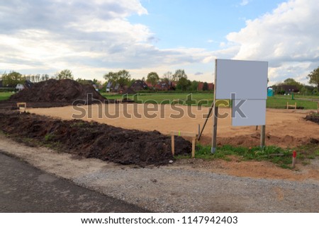 Construction site for one family house filled with sand and empty sign with copy space in building area after earthworks, Germany