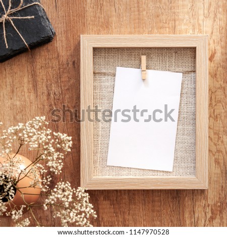 Wooden mockup frame with white flowers in a vase and stone washers tied with string
