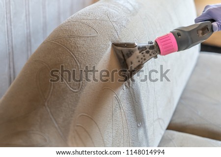 Closeup of upholstered Sofa chemical cleaning with professional extraction method. Man is holding nozzle. Royalty-Free Stock Photo #1148014994