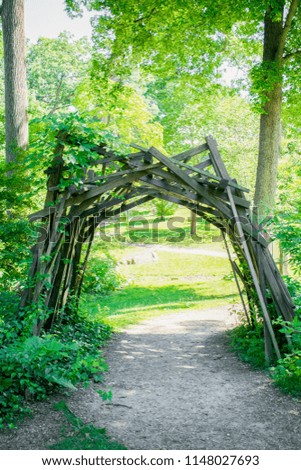 Wooden arch in a beautiful summer forest with path going trough and into far.
